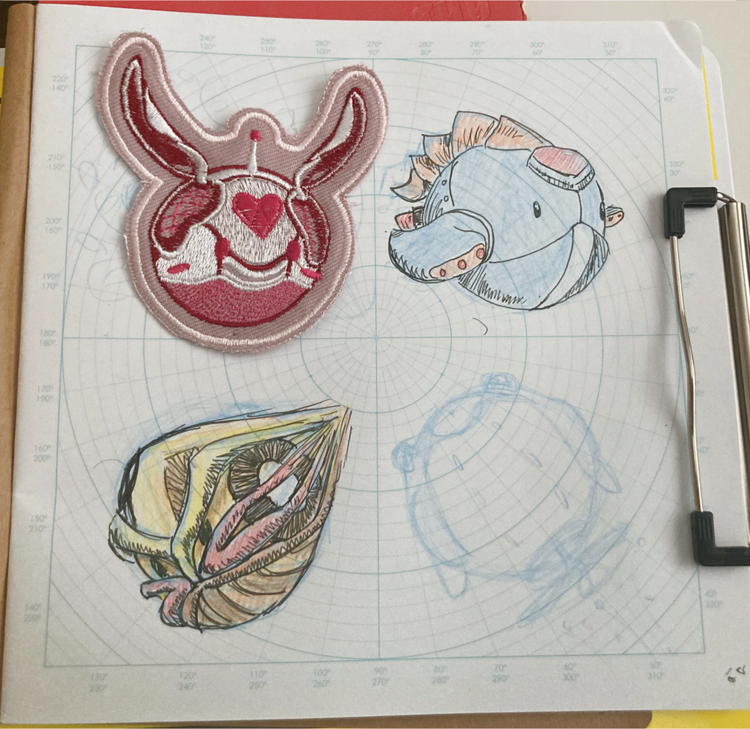 A photograph an embroidered patch and three other sketches arranged in a square. The designs are all small spherical robots. 