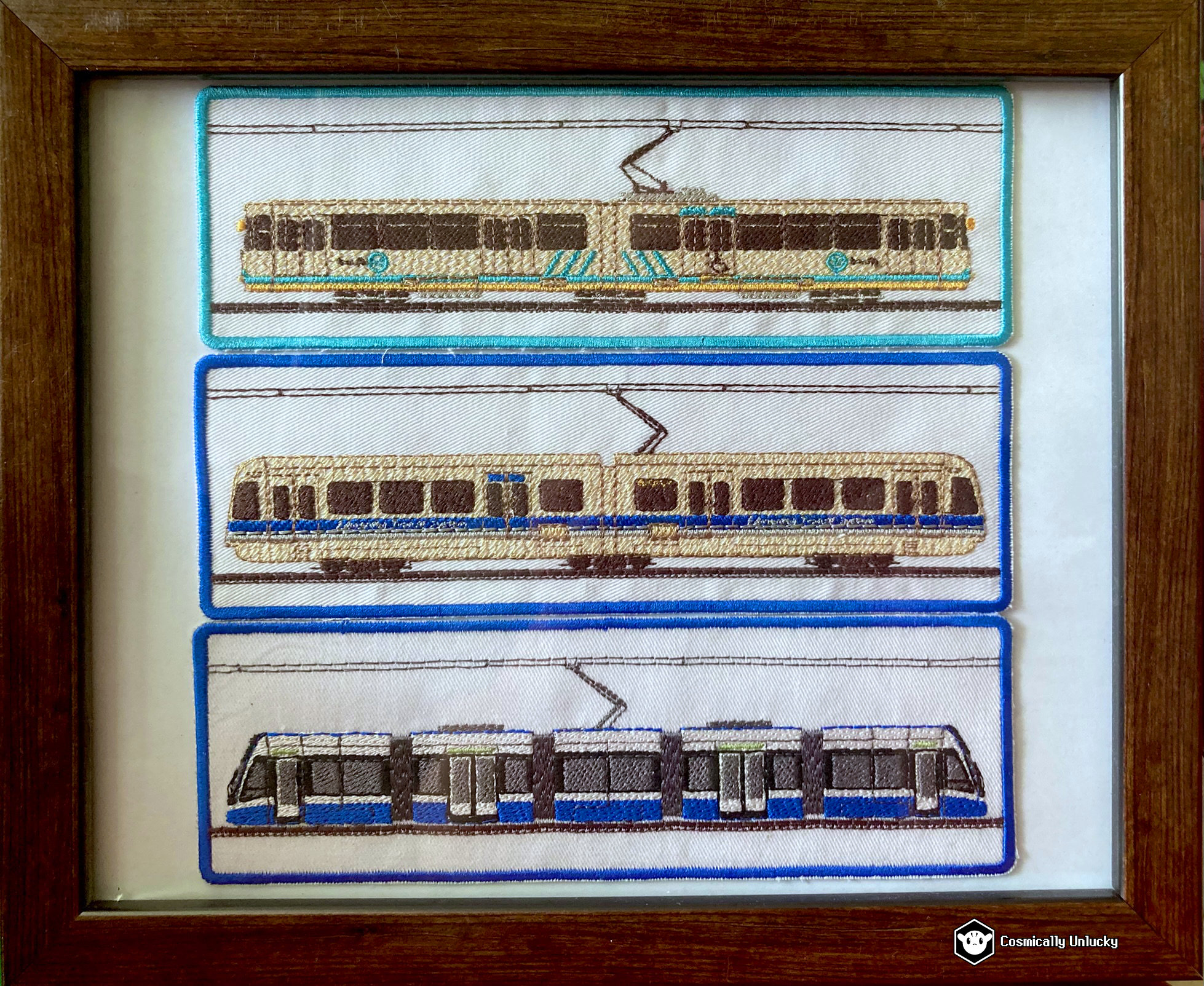 A photograph of a frame containing three Edmonton LRT train patches