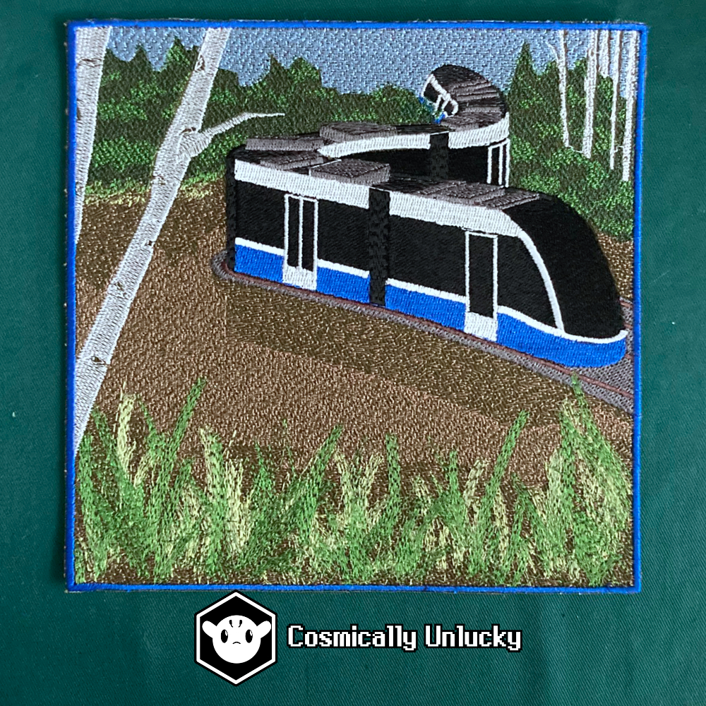 A photograph of a large embroidered patch depicting an LRT train curving through a forested wetland area