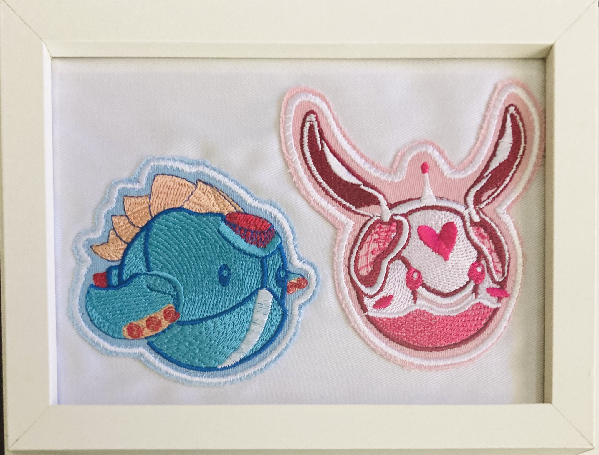 A photograph of a frame containing two embroidered robot patches